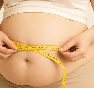 Overweight female measuring stomach with tape